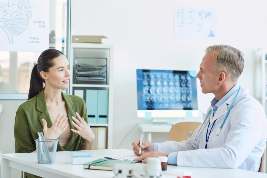Young Woman Talking to Doctor in Clinic